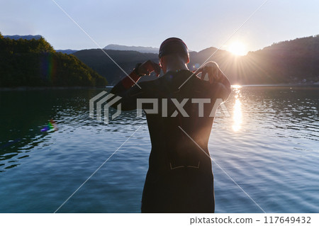 Authentic triathlon athlete getting ready for swimming training on lake 117649432