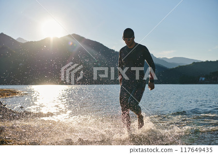 Triathlon athlete starting swimming training on lake Triathlon athlete starting swimming training on lake 117649435