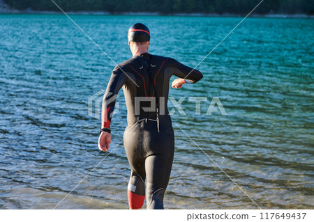 Triathlon athlete starting swimming training on lake 117649437