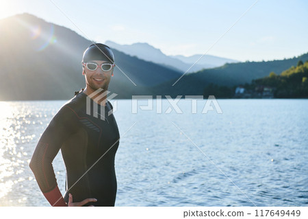 Authentic triathlon athlete getting ready for swimming training on lake Authentic triathlon athlete getting ready for swimming training on lake 117649449