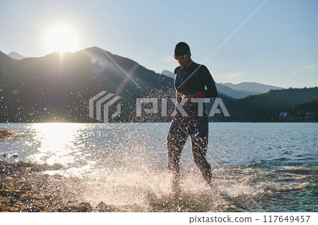 Triathlon athlete starting swimming training on lake Triathlon athlete starting swimming training on lake 117649457