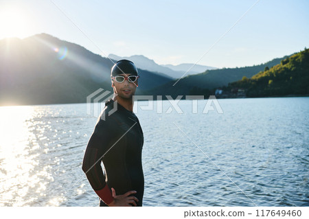 Authentic triathlon athlete getting ready for swimming training on lake 117649460