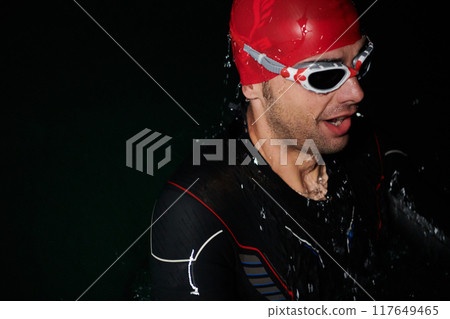 A triathlete finds serene rejuvenation in a lake, basking in the tranquility of the water after an intense training session 117649465
