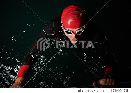 A triathlete finds serene rejuvenation in a lake, basking in the tranquility of the water after an intense training session A triathlete finds serene rejuvenation in a lake, basking in the tranquility of the water after an intense training session 117649476
