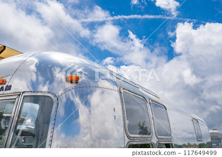 Blue sky reflected in the camping trailer Airstream Aluminum streamlined body 117649499