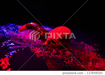 Authentic triathlete swimmer having a break during hard training on night neon gel light 117649503