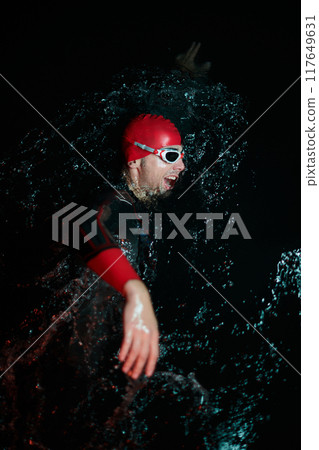Authentic triathlete swimmer having a break during hard training on night neon gel light 117649631