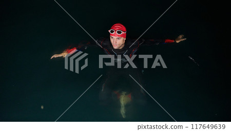 A triathlete finds serene rejuvenation in a lake, basking in the tranquility of the water after an intense training session A triathlete finds serene rejuvenation in a lake, basking in the tranquility of the water after an intense training session 117649639