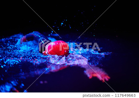 Authentic triathlete swimmer having a break during hard training on night neon gel light 117649663