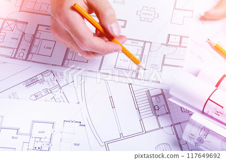 Builder's hands on the background of a house plan. Construction planning. Drawing up an estimate. 117649692