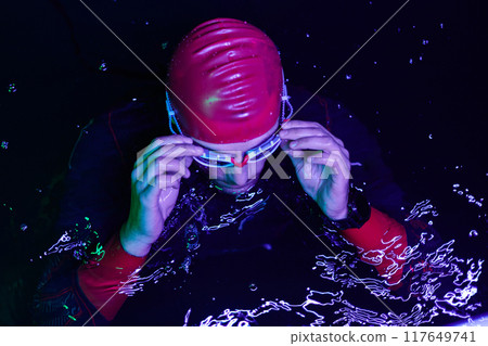 A determined professional triathlete undergoes rigorous night time training in cold waters, showcasing dedication and resilience in preparation for an upcoming triathlon swim competition 117649741