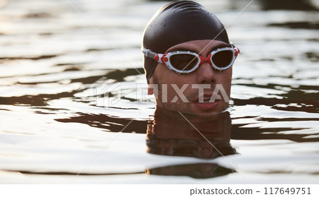 A triathlete finds serene rejuvenation in a lake, basking in the tranquility of the water after an intense training session A triathlete finds serene rejuvenation in a lake, basking in the tranquility of the water after an intense training session 117649751