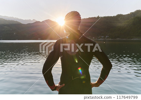 Authentic triathlon athlete getting ready for swimming training on lake 117649799