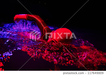 Authentic triathlete swimmer having a break during hard training on night neon gel light 117649809