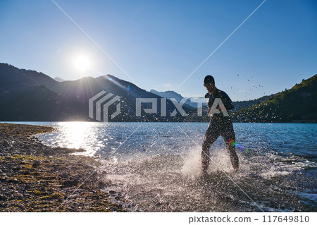 Triathlon athlete starting swimming training on lake Triathlon athlete starting swimming training on lake 117649810