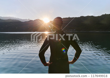 Authentic triathlon athlete getting ready for swimming training on lake Authentic triathlon athlete getting ready for swimming training on lake 117649918