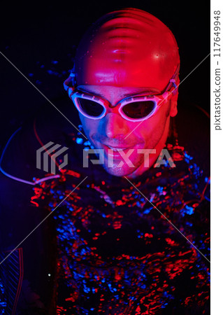 authentic triathlete swimmer having a break during hard training on night neon gel light 117649948