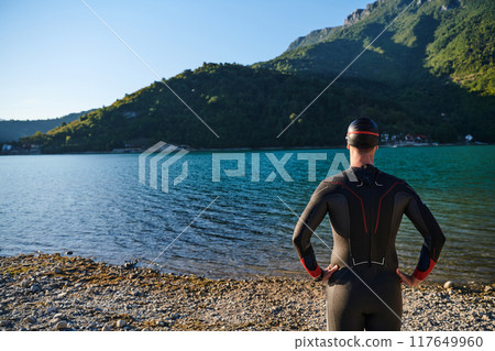 Authentic triathlon athlete getting ready for swimming training on lake 117649960