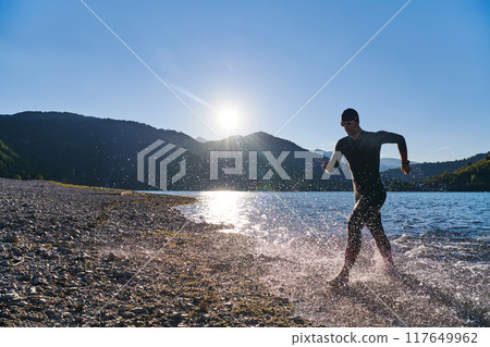 Triathlon athlete starting swimming training on lake Triathlon athlete starting swimming training on lake 117649962