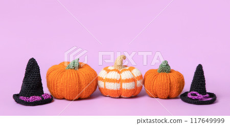 Knitted orange pumpkins with black witch hat on purple background, autumn composition, front view. Halloween concept. Knitted orange pumpkins with black witch hat on purple background, autumn composition, front view. Halloween concept. 117649999