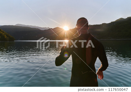 Authentic triathlon athlete getting ready for swimming training on lake 117650047