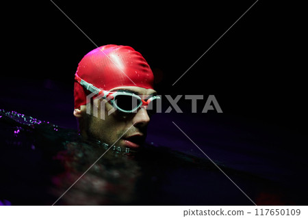 A determined professional triathlete undergoes rigorous night time training in cold waters, showcasing dedication and resilience in preparation for an upcoming triathlon swim competition 117650109