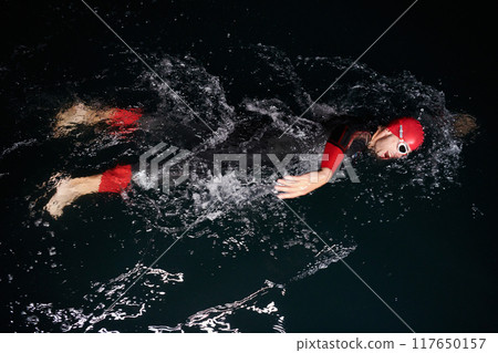 authentic triathlete swimmer having a break during hard training on night neon gel light 117650157