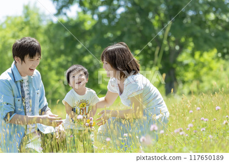 Three-person family playing in a fresh green park Three-person family playing in a fresh green park 117650189