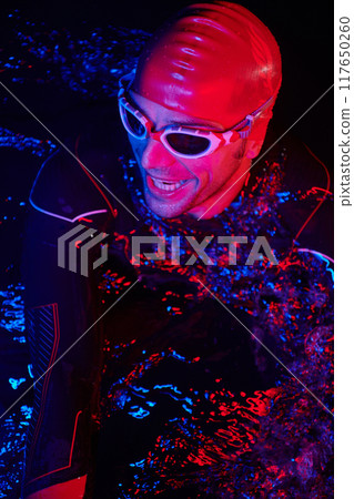 authentic triathlete swimmer having a break during hard training on night neon gel light 117650260