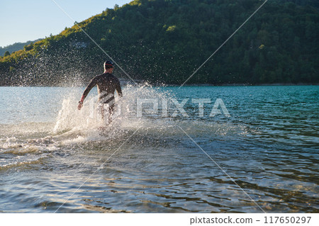 Triathlon athlete starting swimming training on lake 117650297