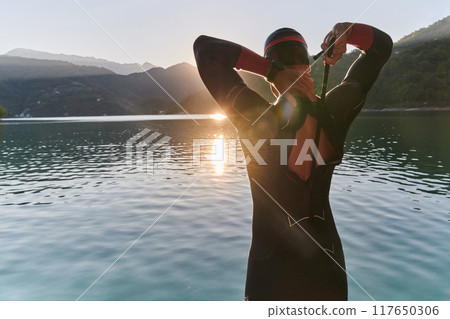 Authentic triathlon athlete getting ready for swimming training on lake 117650306