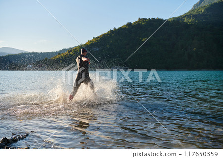 Triathlon athlete starting swimming training on lake 117650359