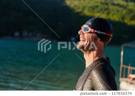 Authentic triathlon athlete getting ready for swimming training on lake Authentic triathlon athlete getting ready for swimming training on lake 117650374