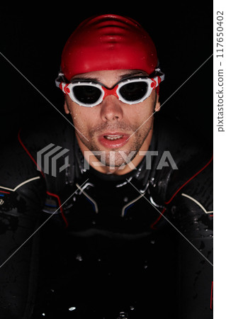 A determined professional triathlete undergoes rigorous night time training in cold waters, showcasing dedication and resilience in preparation for an upcoming triathlon swim competition 117650402