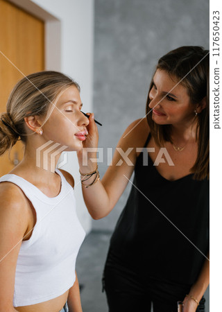 Makeup artist applies eye shadow to another woman 117650423