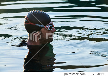 A triathlete finds serene rejuvenation in a lake, basking in the tranquility of the water after an intense training session A triathlete finds serene rejuvenation in a lake, basking in the tranquility of the water after an intense training session 117650496