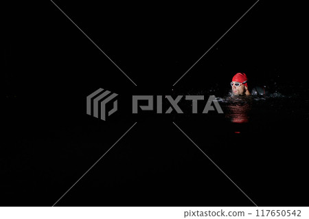 Authentic triathlete swimmer having a break during hard training on night Authentic triathlete swimmer having a break during hard training on night 117650542