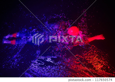 Authentic triathlete swimmer having a break during hard training on night neon gel light 117650574