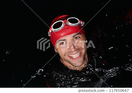 Authentic triathlete swimmer having a break during hard training on night Authentic triathlete swimmer having a break during hard training on night 117650647