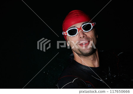 A triathlete finds serene rejuvenation in a lake, basking in the tranquility of the water after an intense training session 117650666