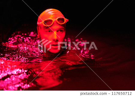 authentic triathlete swimmer having a break during hard training on night neon gel light 117650712