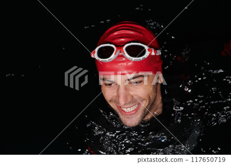 Authentic triathlete swimmer having a break during hard training on night Authentic triathlete swimmer having a break during hard training on night 117650719