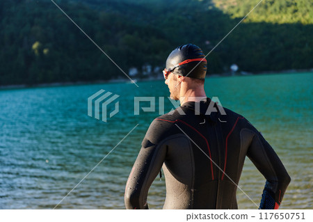 Authentic triathlon athlete getting ready for swimming training on lake 117650751