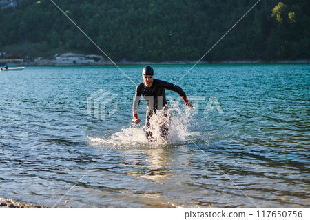 Triathlon athlete starting swimming training on lake 117650756
