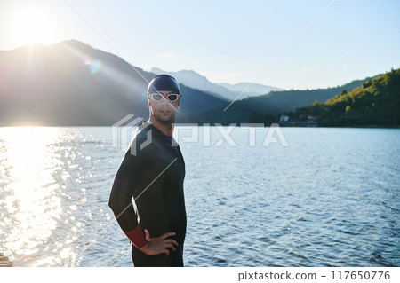 Authentic triathlon athlete getting ready for swimming training on lake Authentic triathlon athlete getting ready for swimming training on lake 117650776