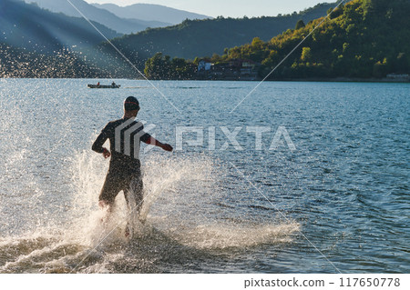 Triathlon athlete starting swimming training on lake Triathlon athlete starting swimming training on lake 117650778
