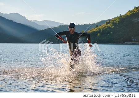 Triathlon athlete starting swimming training on lake Triathlon athlete starting swimming training on lake 117650811
