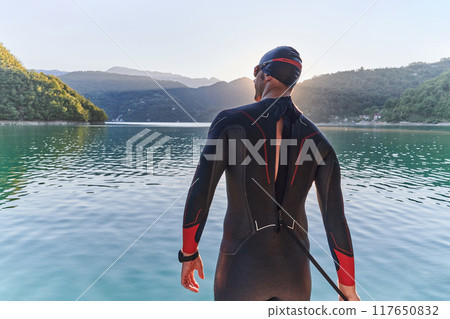 Authentic triathlon athlete getting ready for swimming training on lake 117650832
