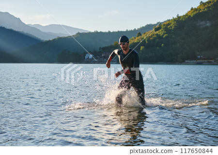 Triathlon athlete starting swimming training on lake Triathlon athlete starting swimming training on lake 117650844