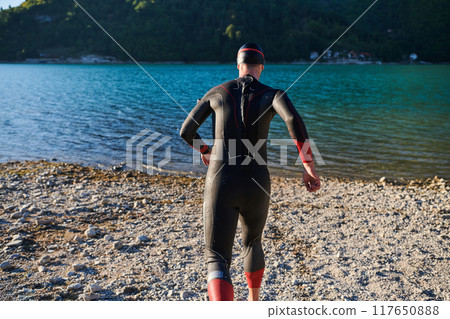 Authentic triathlon athlete getting ready for swimming training on lake Authentic triathlon athlete getting ready for swimming training on lake 117650888